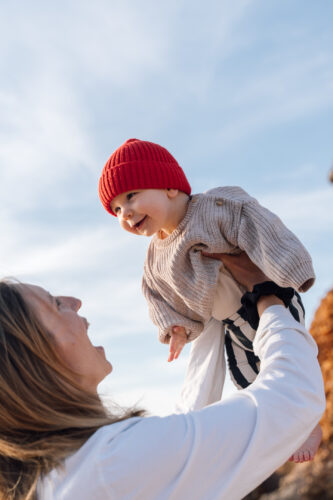 Mother lifting her baby up against a blue sky during an Algarve family photoshoot