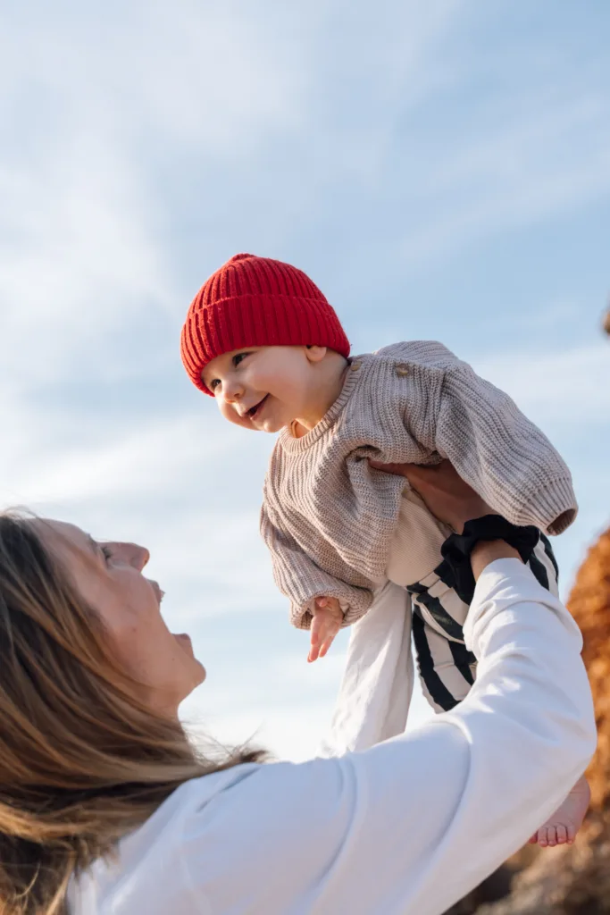 Mother lifting her baby up against a blue sky during an Algarve family photoshoot