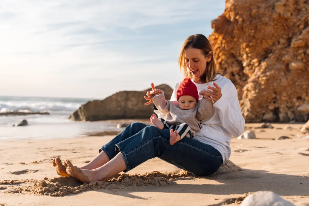 Mother and baby playing on the sand beside the cliffs during a Sagres family photoshoot