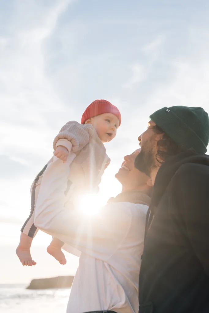 Parents lifting their baby into the sunlight during a Lagos family photoshoot in the Algarve